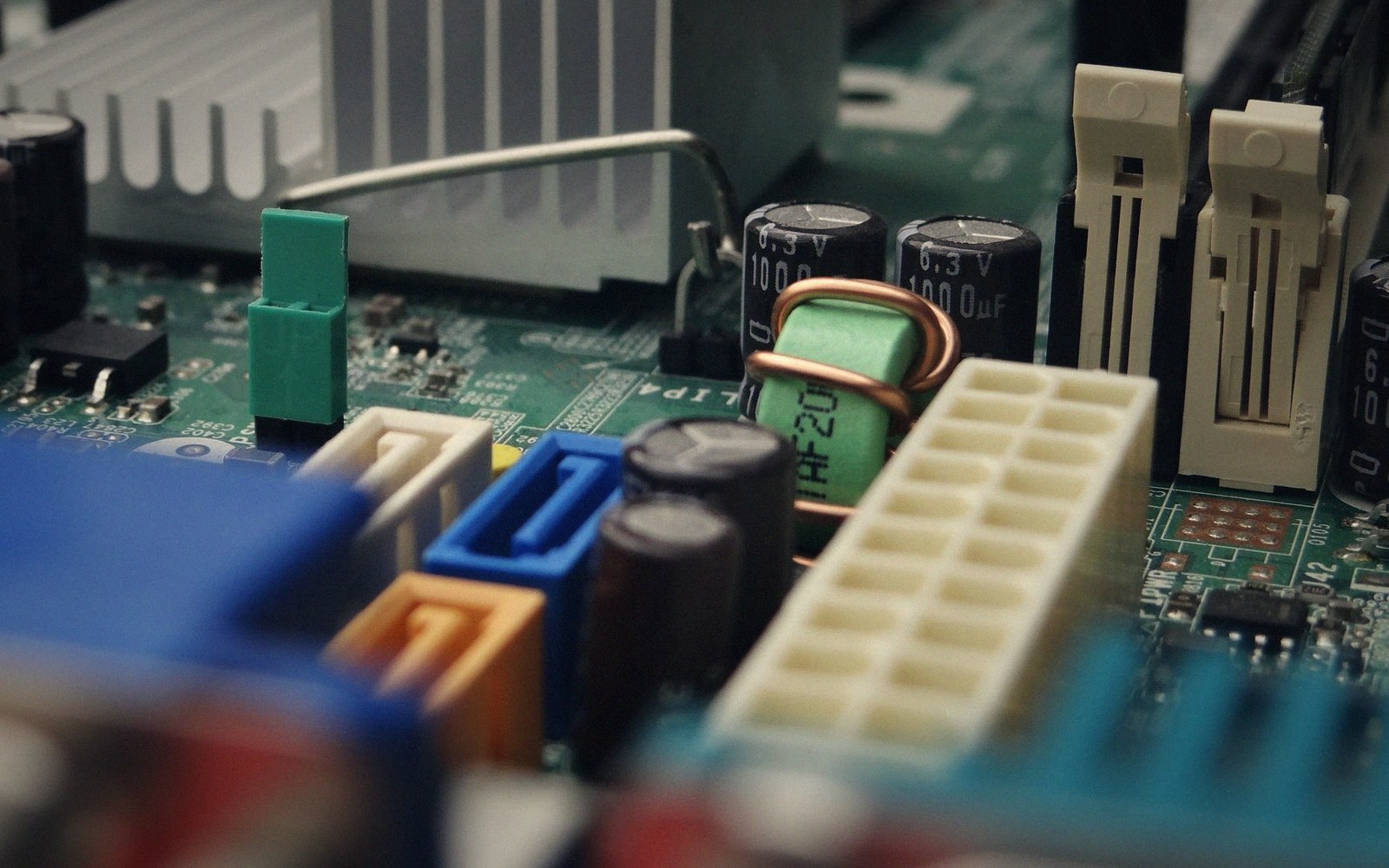 Close-up of a computer motherboard showing capacitors, connectors, and a heat sink